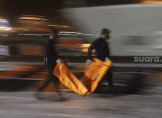 Petugas DVI Polri membawa kantong jenazah berisi bagian tubuh korban pesawat Sriwijaya Air SJ 182 rute Jakarta - Pontianak yang hilang kontak di perairan Kepulauan Seribu, di Dermaga JICT, Tanjung Priok, Jakarta, Senin (11/1/2021). [Suara.com/Angga Budhiyanto]
