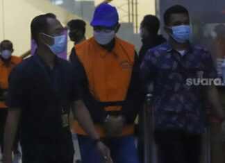 Gubernur Sulawesi Selatan, Nurdin Abdullah berjalan dengan mengenakan rompi orange setelah menjalani pemeriksaan di Gedung KPK, Jakarta Selatan, Minggu (28/2/2021). [Suara.com/Alfian Winanto]