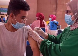 Vaksinator memberikan suntikan vaskin Covid-19 dalam acara vaksinasi massal petugas pelayanan publik, TNI hingga wartawan di Pusat Pemerintahan Kota Tangerang, Jumat (26/2/2021). [Suara.com/Muhammad Jehan Nurhakim]