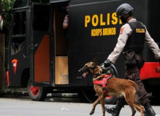 Anggota polisi berjalan dengan anjing pelacak saat mengumpulkan sisa serpihan ledakan bom bunuh diri di depan Gereja Katedral Makassar, Sulawesi Selatan, Senin (29/3/2021). ANTARA FOTO/Arnas Padda