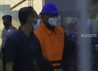 Gubernur Sulawesi Selatan, Nurdin Abdullah berjalan dengan mengenakan rompi orange setelah menjalani pemeriksaan di Gedung KPK, Jakarta Selatan, Minggu (28/2/2021). [Suara.com/Alfian Winanto]